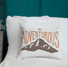 Load image into Gallery viewer, A pillow on a bed with the phrase “Be adventurous” with arrows pointing to the word “be” and a brown mountain illustration underneath the word “adventure.” The pillow is white. 