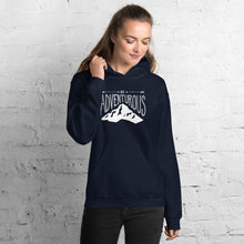 Load image into Gallery viewer, A woman wearing a navy hoodie with lettering and illustration in white with the phrase “Be Adventurous” with arrows pointing to the word “be” and a mountain illustration underneath the word “adventure.”