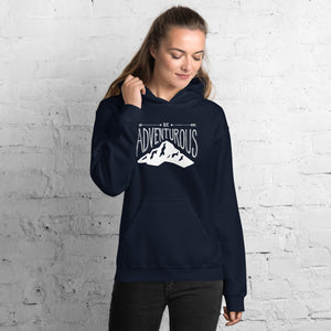 A woman wearing a navy hoodie with lettering and illustration in white with the phrase “Be Adventurous” with arrows pointing to the word “be” and a mountain illustration underneath the word “adventure.”