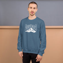 Load image into Gallery viewer, A man wearing an indigo blue hoodie with lettering and illustration in white with the phrase “Be Adventurous” with arrows pointing to the word “be” and a mountain illustration underneath the word “adventure.”