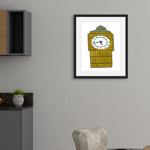 All illustration of Big Ben featured in a black frame on a kitchen wall. The frame is above a kitchen table with kitchen cabinets on the side. 