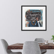 Load image into Gallery viewer, A black frame featured on a wall above a kitchen table. The artwork in the frame is an illustrated image of a boombox with a person wearing a gold chain and blue jacket. 