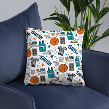 Load image into Gallery viewer, A white pillow featuring colorful basketball illustrations sits on a dark navy sofa chair with a plant in the background.