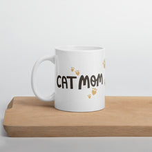 Load image into Gallery viewer, A white ceramic mug with black lettering with the words Cat Mom. Light gold colored heart shaped paws surround the Cat Mom words. This is a fun gift for cat lovers. 
