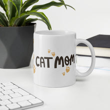 Load image into Gallery viewer, A white ceramic mug with the phrase Cat Mom in black letters with red heart shaped paws around the words. The mug makes a lovely gift for a cat owner.
