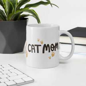A white ceramic mug with the phrase Cat Mom in black letters with red heart shaped paws around the words. The mug makes a lovely gift for a cat owner.