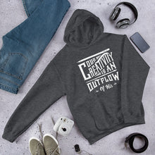 Load image into Gallery viewer, A dark grey hoodie laying on the ground with objects around it. The hoodie features hand drawn lettering in white with the words &quot;Our creativity is an outflow of His.&quot;