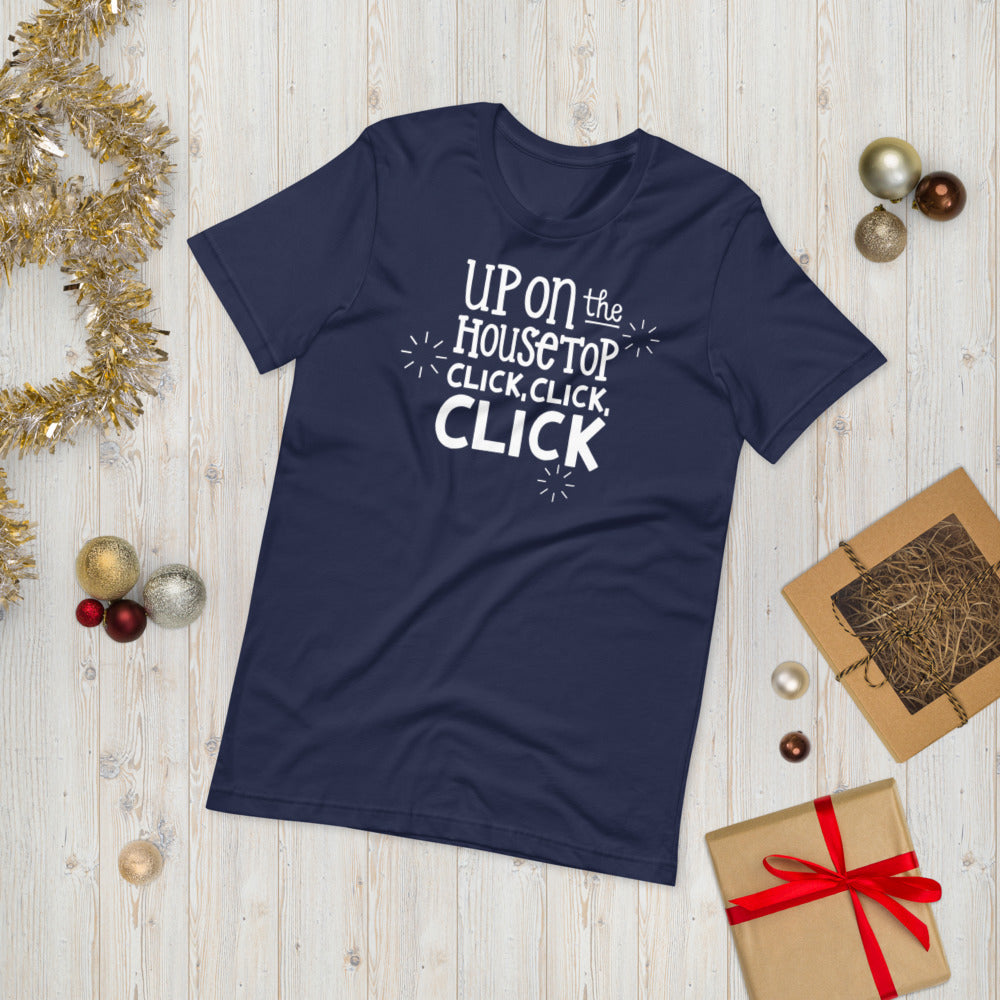 A navy T-shirt laying on the ground with Christmas items surrounding it. The T-shirt features the words  