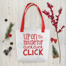 Load image into Gallery viewer, A white tote bag with red handles laying on a table with Christmas items around it. The tote bag features the words &quot;Up on the housetop, click, click, click&quot; in red lettering. There are there blue stars around the the words. 