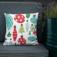 Load image into Gallery viewer, The white pillow is leaning on a sofa with a plant off to the side. The pillow is white with illustrations in the colors red, light green and dark green, blue and light blue. The pattern features vintage Christmas ornaments. 