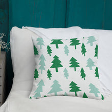 Load image into Gallery viewer, A white pillow with illustrations leading on white bedding with a side table off to the side. The white pillow features illustrated pine trees in dark and light green. 