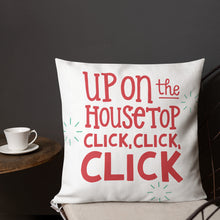 Load image into Gallery viewer, A pillow on a chair with a coffee mug on a table next to it. The red pillow features the song lyric &quot;Up on the housetop, click, click, click&quot; in red lettering. There are three star patterns in blue around the words. 