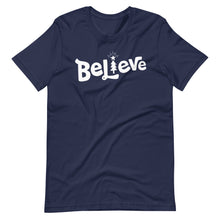 Load image into Gallery viewer, A navy T-shirt on a white background. The red shirt features the hand lettered word &quot;Believe&quot; in white with the &quot;I&quot; featured as an illustrated Christmas tree. 