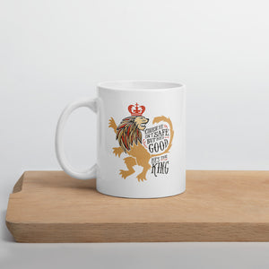 A white mug sitting on a wood cutting board. The mug artwork features hand drawn illustration of the Chronicles of Narnia lion character Aslan. Inside the illustration there is the quote "Course He Isn't Safe, But He's Good. He's the King."