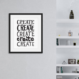 Artwork featured in a black frame on a wall featured with shelves in the background. The artwork is on a white paper with black lettering in the word “create” written five times. 