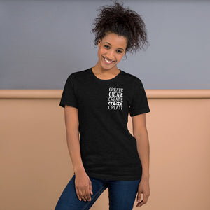 A woman wearing a black blue short sleeved t-shirt. The tee features the lettering and illustration in white. The phrase "create, create, create, create, create" is in a small rectangle on the upper left side. 