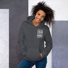 Load image into Gallery viewer, A woman wearing a dark grey hoodie with the word &quot;create, create, create, create, create&quot; in white in a small rectangle on the upper left side.