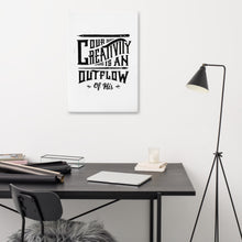 Load image into Gallery viewer, A canvas on a wall above a desk. The canvas is white and features hand drawn lettering featuring &quot;Our creativity is an outflow of His.&quot; The lettering is in black. 