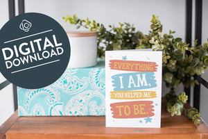 A greeting card is on a table top with a present in blue wrapping paper in the background. On top of the present is a candle and some greenery from a plant too. The card features the words “Everything I Am, You Helped Me To Be.” The words "digital download" are featured in a circle on top of the image. 