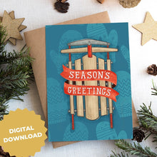 Load image into Gallery viewer, A photo of a Christmas card on top of a brown paper wrapped gift with Christmas decor around it. The card has a blue background with lighter blue winter mittens in a pattern. On top of the mittens is an illustrated vintage sled with red ribbon and the words &quot;season&#39;s greetings&quot; in white. The words &quot;digital download&quot; are in the lefthand corner of the image.