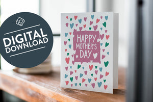 A card on a wood tabletop with an object in the background that is out of focus. The card features the words “Happy Mother’s Day.” The words "digital download" are featured in a circle on top of the image. 