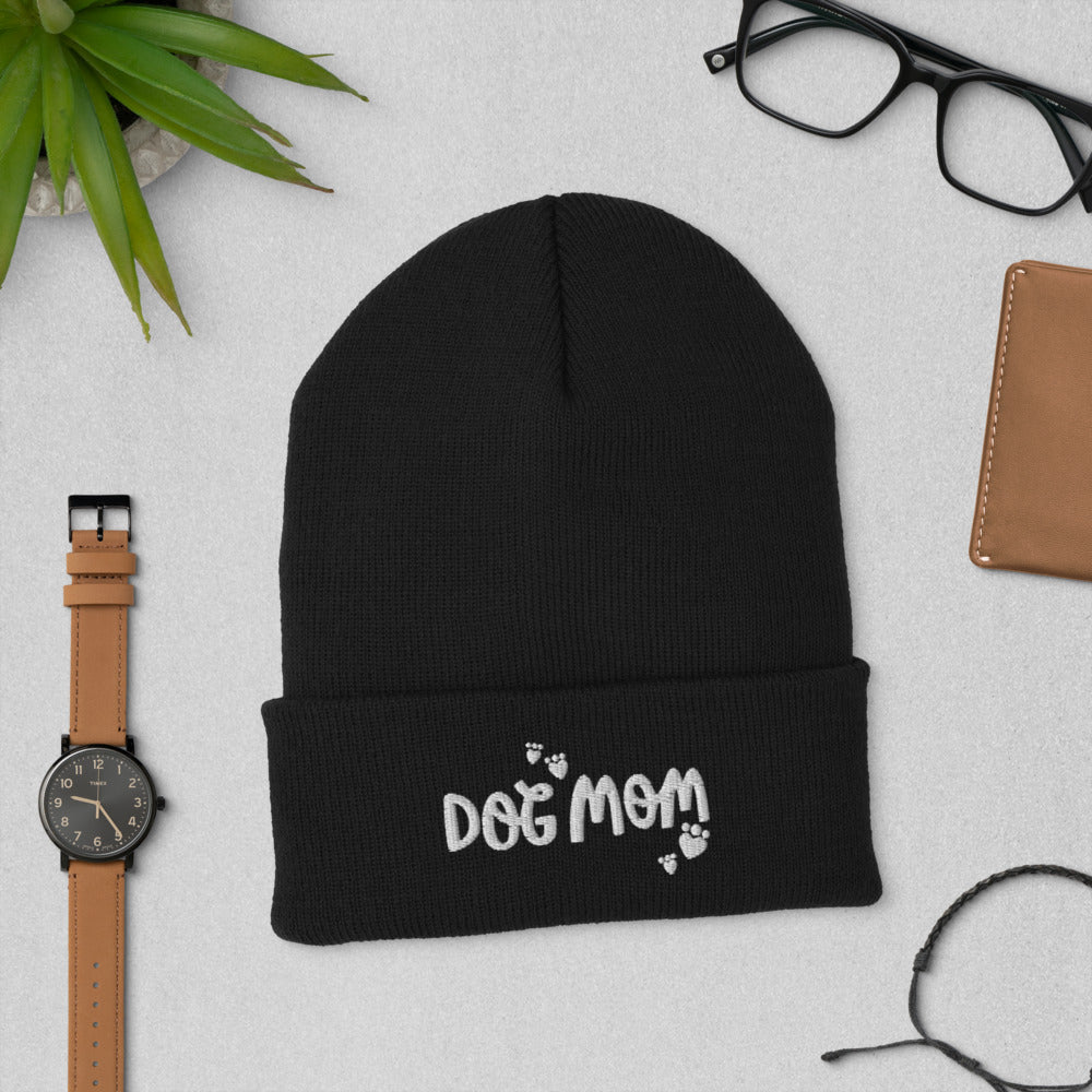 A black colored winter beanie hat with Dog Mom featured on the cuff of the hat. Small hearts in the shape of paws are around the Dog Mom words. This makes a fun gift for any dog mom you know. 