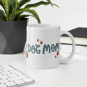 A white ceramic mug with the phrase Dog Mom in black letters with red heart shaped paws around the words. The mug makes a lovely gift for a dog owner. 