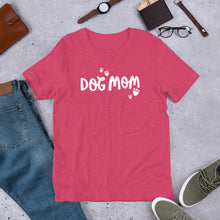 Load image into Gallery viewer, This T-shirt is a raspberry heather color with the words Dog Mom featured in white with small white hearts shaped like paws surrounding it. This shirt makes a fun gift for dog lovers. 