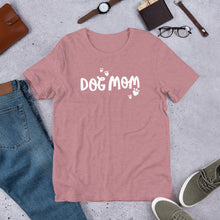 Load image into Gallery viewer, This T-shirt is super soft and comes in a heather orchid color with the words Dog Mom in white surrounded by heart-shaped paws. The T-shirt makes a fun gift for dog owners. 