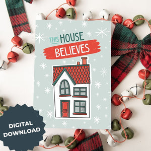A Christmas card featured on top of some red and white Christmas decorations. The Christmas card has a light blue background with stars. The words "this house believes" is featured above an illustrated house. The words and house are in white, green and light blue. The words "digital download" are featured in the lefthand corner over the image.