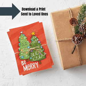 A stack of Christmas cards with brown string wrapped around them. A brown craft paper gift is off to the side. The Christmas card has a red background with two illustrated cute Christmas trees and the words "Be Merry" in white. An arrow with the words "download & print, send to loved ones" above the image.