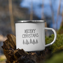 Load image into Gallery viewer, White enamel mug sitting on top of a tree branch with moss in the background. The design on the mug is featured in black reading &quot;Merry Christmas&quot; with modern illustrated trees below the words. 