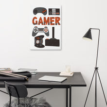 Load image into Gallery viewer, A canvas on a wall above a desk. The canvas is white and features hand drawn lettering and illustrations featuring different game controllers and the word &quot;gamer.&quot; The illustrations and gamer word are in red, grey and black. 