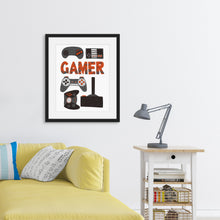Load image into Gallery viewer, Framed artwork in a black frame on a wall above a sofa featuring a white paper print with hand drawn lettering and illustrations with different game controllers and the word &quot;gamer.&quot; The illustrations and gamer word are in red, grey and black. 