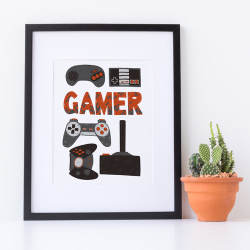 Artwork in a white frame with the artwork printed on white paper and hand drawn lettering and illustrations featuring different game controllers and the word 