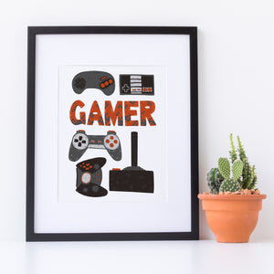 Artwork in a white frame with the artwork printed on white paper and hand drawn lettering and illustrations featuring different game controllers and the word "gamer." The illustrations and gamer word are in red, grey and black. 