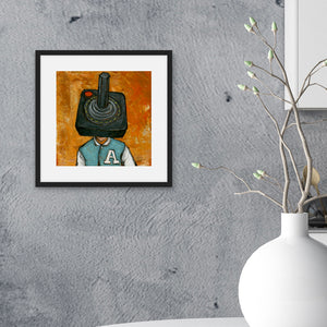 A black from on a grey wall of a kitchen. The illustrated artwork features an Atari controller as a "head" on a person. 