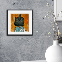 Load image into Gallery viewer, A black from on a grey wall of a kitchen. The illustrated artwork features an Atari controller as a &quot;head&quot; on a person.