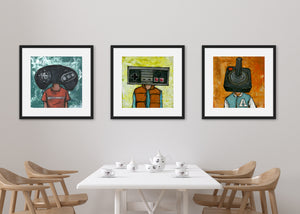 Three black frames on a wall above a kitchen table. Three black frames featuring a vintage Nintendo controller, the second frame a Sega Genesis original controller, and the third frame is an Atari frame. 