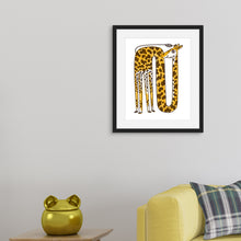 Load image into Gallery viewer, A black frame on a wall with a yellow giraffe illustration. The frame is on the wall above a yellow sofa and side table.