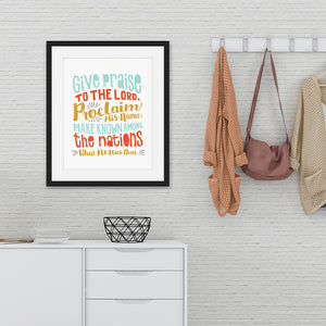 Hand drawn lettering artwork in a black frame over a chest of drawers. The artwork has the Bible verse Psalm 105:1 "Give praise to the Lord, proclaim his name; make known among the nations what he has done."