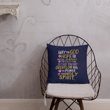 Load image into Gallery viewer, A pillow on a chair with a coffee mug on a table next to it. The purple pillow features hand drawn lettering of the Bible verse &quot;May the God of hope fill you with all joy and peace as you trust him, so that you may overflow with hope by the power of the holy spirit.&quot; The lettering in white, pink and yellow. 