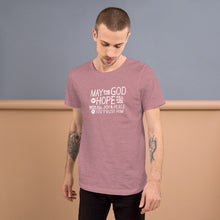 Load image into Gallery viewer, A man wearing an orchid pink color short sleeved t-shirt. The t-shirt features hand drawn lettering in white with the words &quot;May the God of hope fill you with all joy and peace as you trust him.&quot;