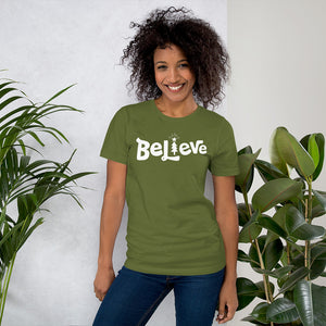 A woman wearing an olive green short sleeved t-shirt. The tee features lettering of the word "Believe" in white with the "I" of the word featured as an illustrated Christmas tree. 