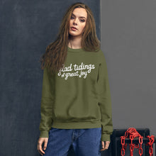 Load image into Gallery viewer, A woman wearing a green sweatshirt featuring hand drawn lettering with the words &quot;glad tidings of great joy&quot; in white. 
