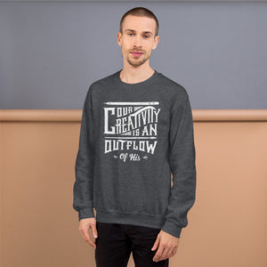 A man wearing a dark grey sweatshirt featuring hand drawn lettering in white with the words "Our creativity is an outflow of His."
