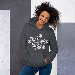 A woman wearing a dark grey hoodie featuring hand drawn lettering in white reading Dashing through the snow. There are white snowflakes around the words. 