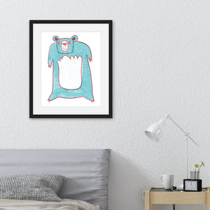 An illustration of a blue bear in a black frame. The frame is hanging on the wall above a bed with a grey headboard.
