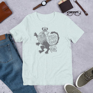 A prism ice blue short sleeved T-shirt laying flat with objects around it. The T-Shirt features hand drawn illustration of the Chronicles of Narnia lion character Aslan. Inside the illustration there is the quote "Course He Isn't Safe, But He's Good. He's the King."