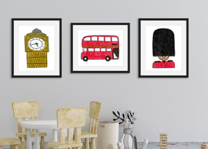 Frames with artwork shown in a kids playroom with a small table and toys. Three black frames with London illustrations in the frame. The first illustration is a queen's guard, the second a red double decker bus and the third, an illustration of Big Ben.